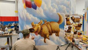 Crews install painted Russell and Dug panels on the Wilderness Explorers Sky Swings structure at Disney Adventure World